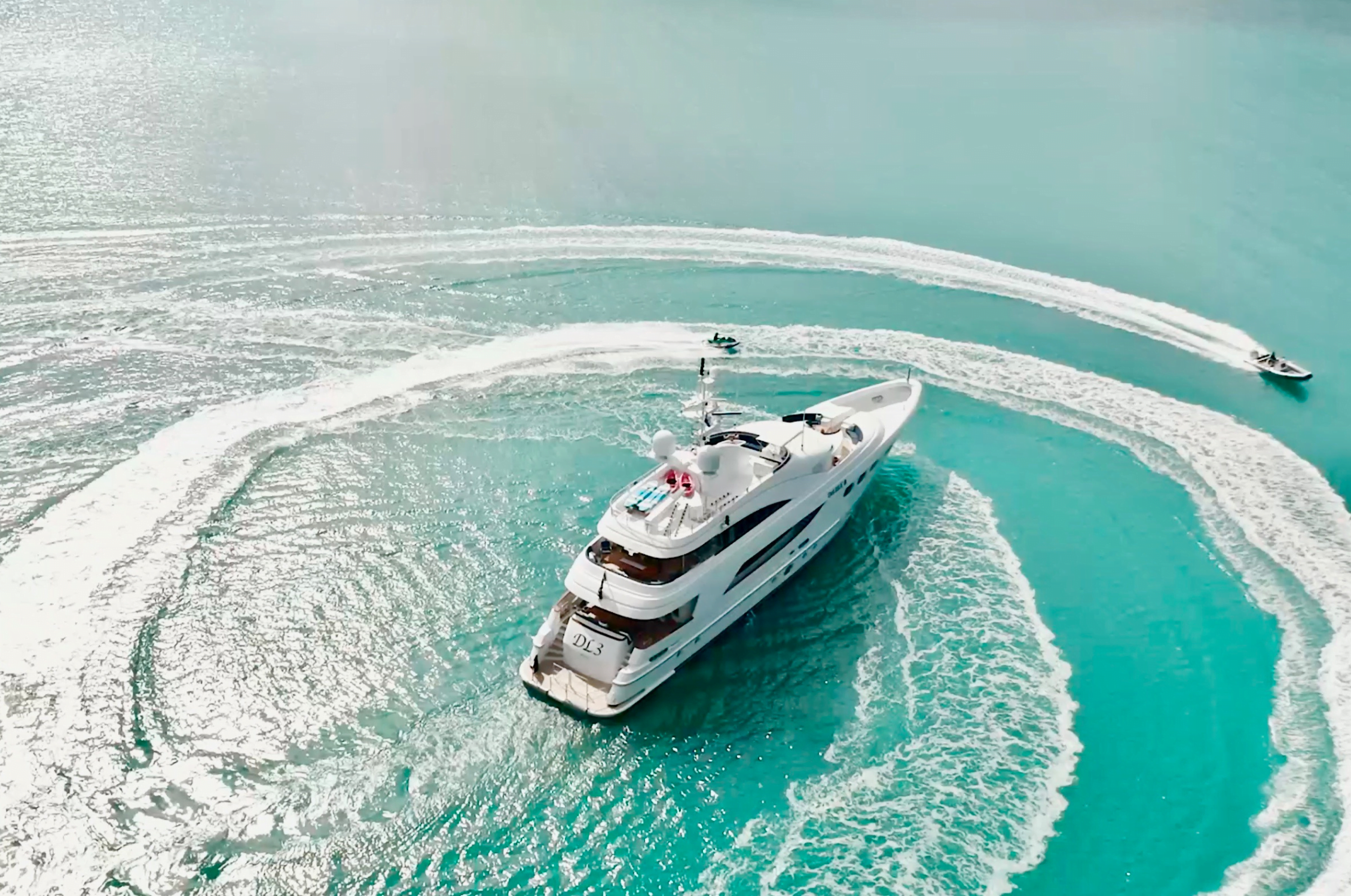 Guests circling superyacht in turquoise waters.