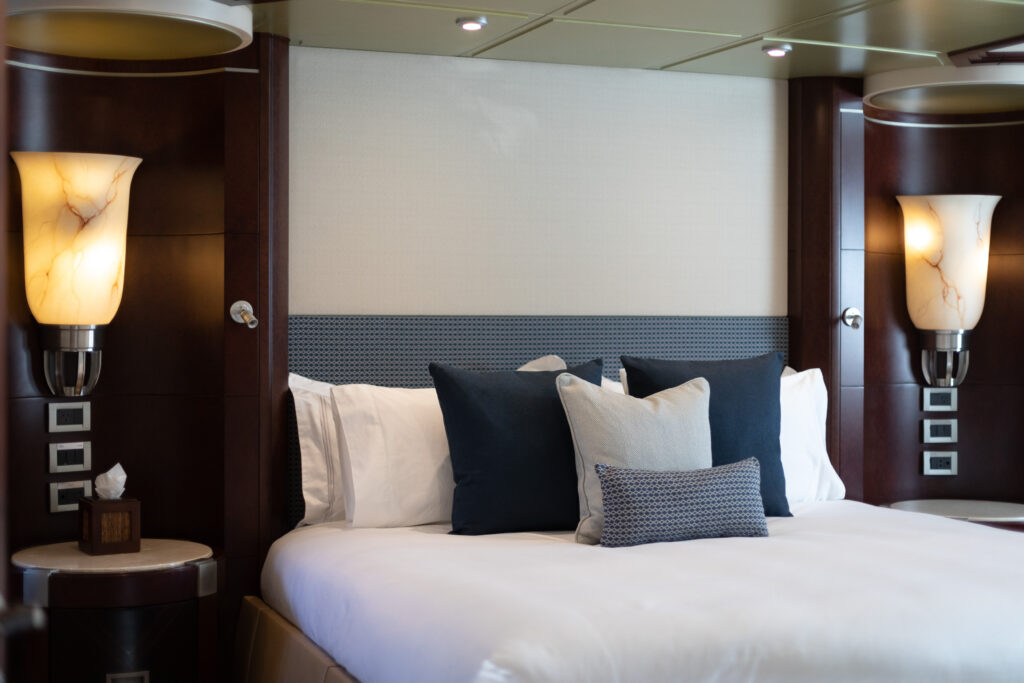 master cabin in superyacht with wall scones and blue pillows